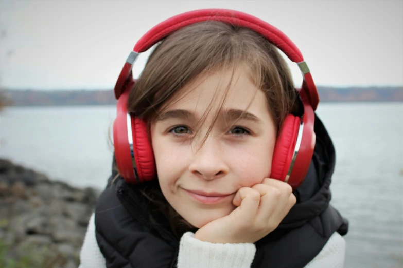 a  with red headphones on is standing by the water