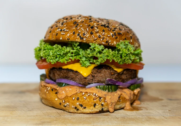 the large hamburger has several lettuce, tomatoes and onions