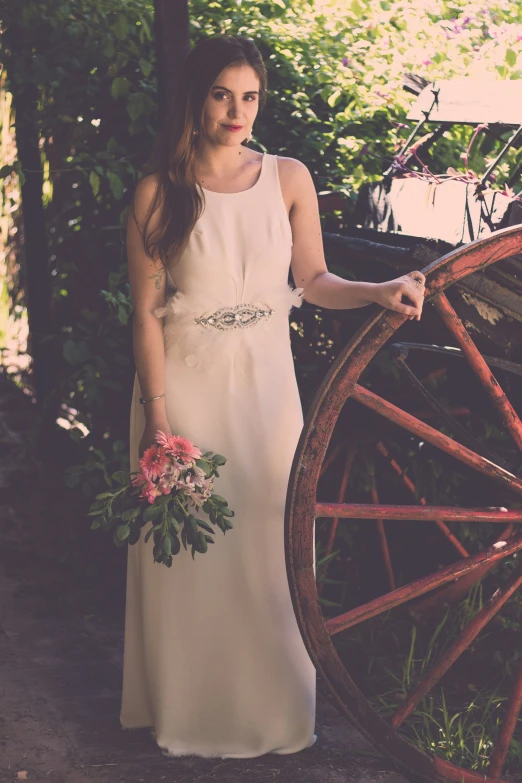 a young woman is holding an antique wagon wheel