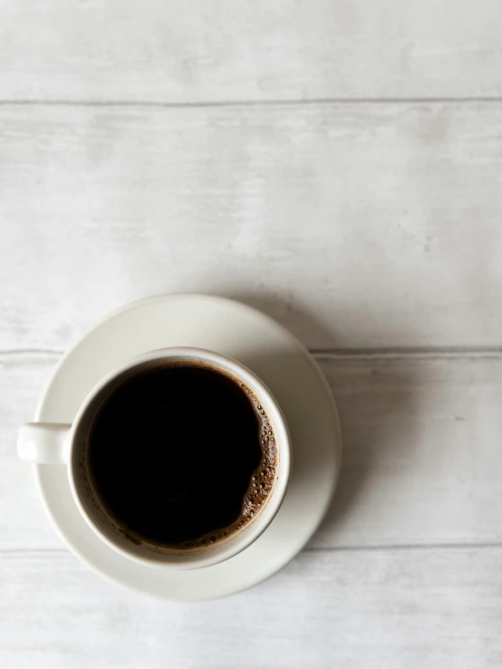 a cup of black coffee sits on a table