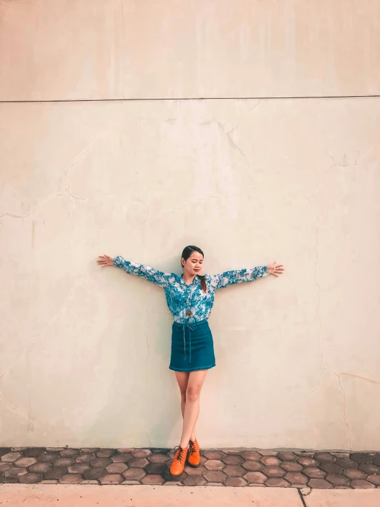 a woman with her arms outstretched in front of a wall