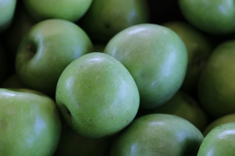 a bunch of green apples stacked on top of each other