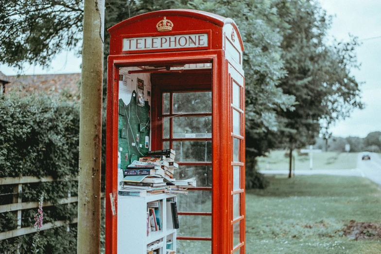 a red telephone booth that has some type of newspaper on it