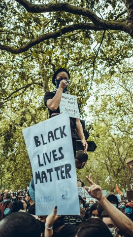 protestors are protesting in public as a black lives matter sign holds up a woman