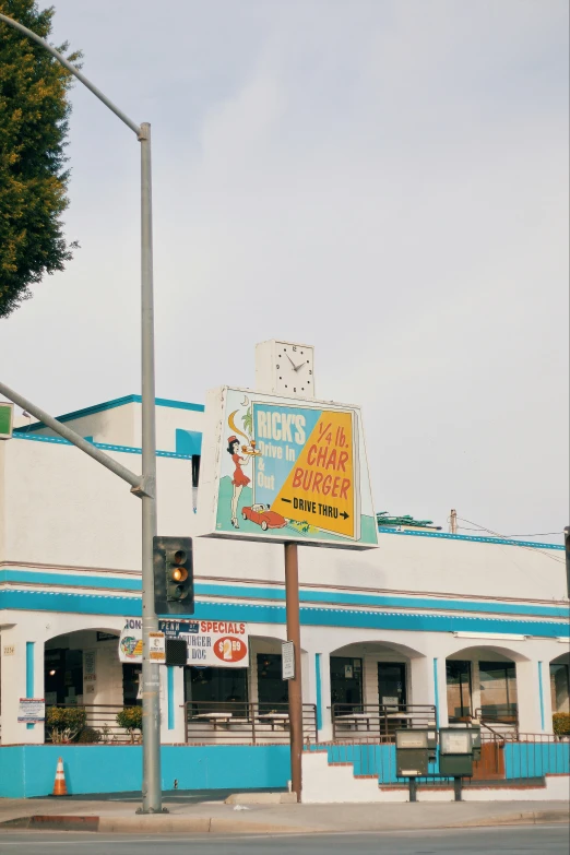 an old blue and white building with a colorful sign on the corner