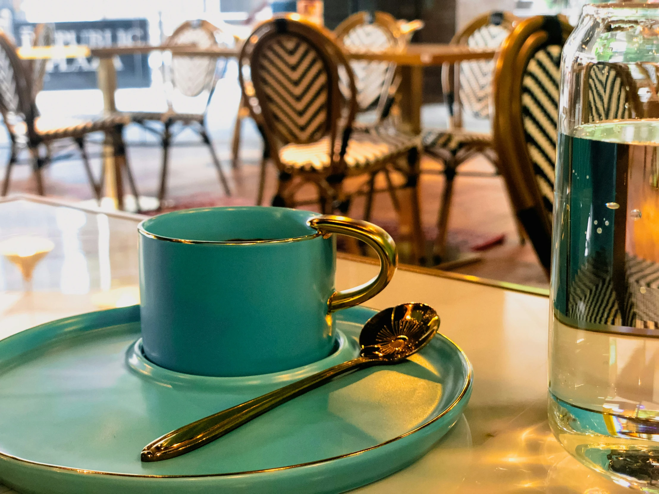 a blue plate with gold trim and a coffee cup with a spoon