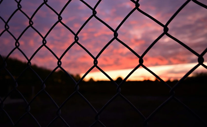 a fence with clouds in the sky