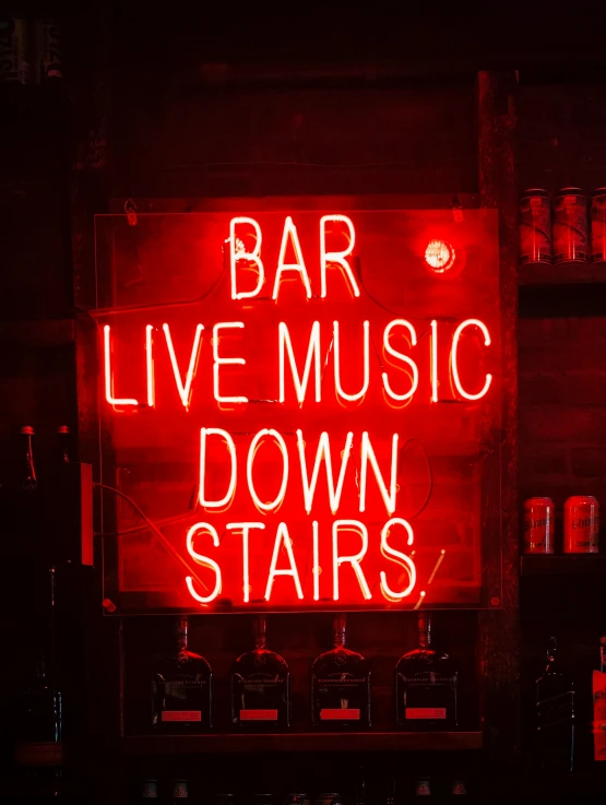 a lighted sign in the shape of a bar with live music down stairs