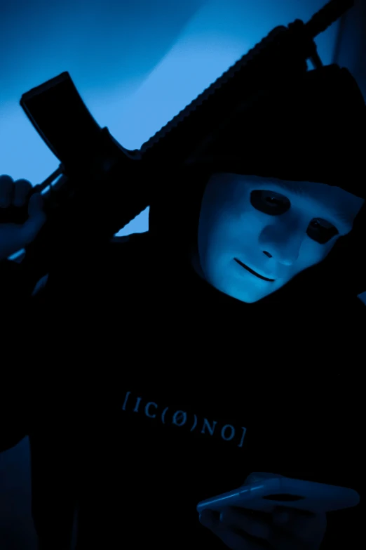 a person wearing a mask holding a gun and cell phone