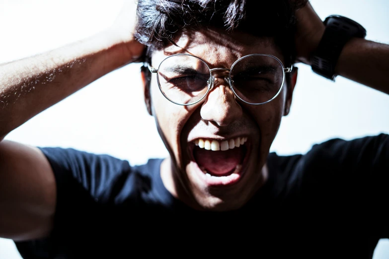 a young man with glasses making an open face