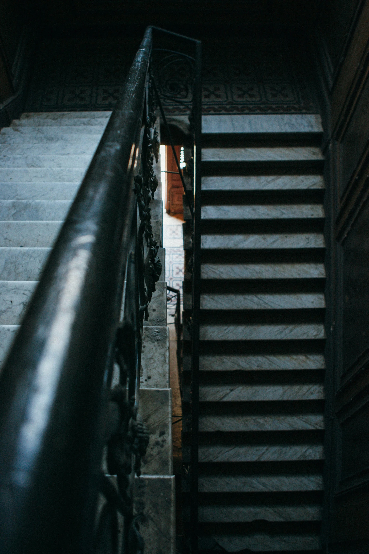 staircase in a dark setting with a wrought iron railing and handrail