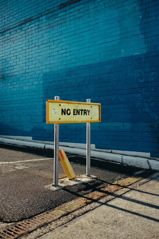 there is no entry sign sitting next to a blue brick wall