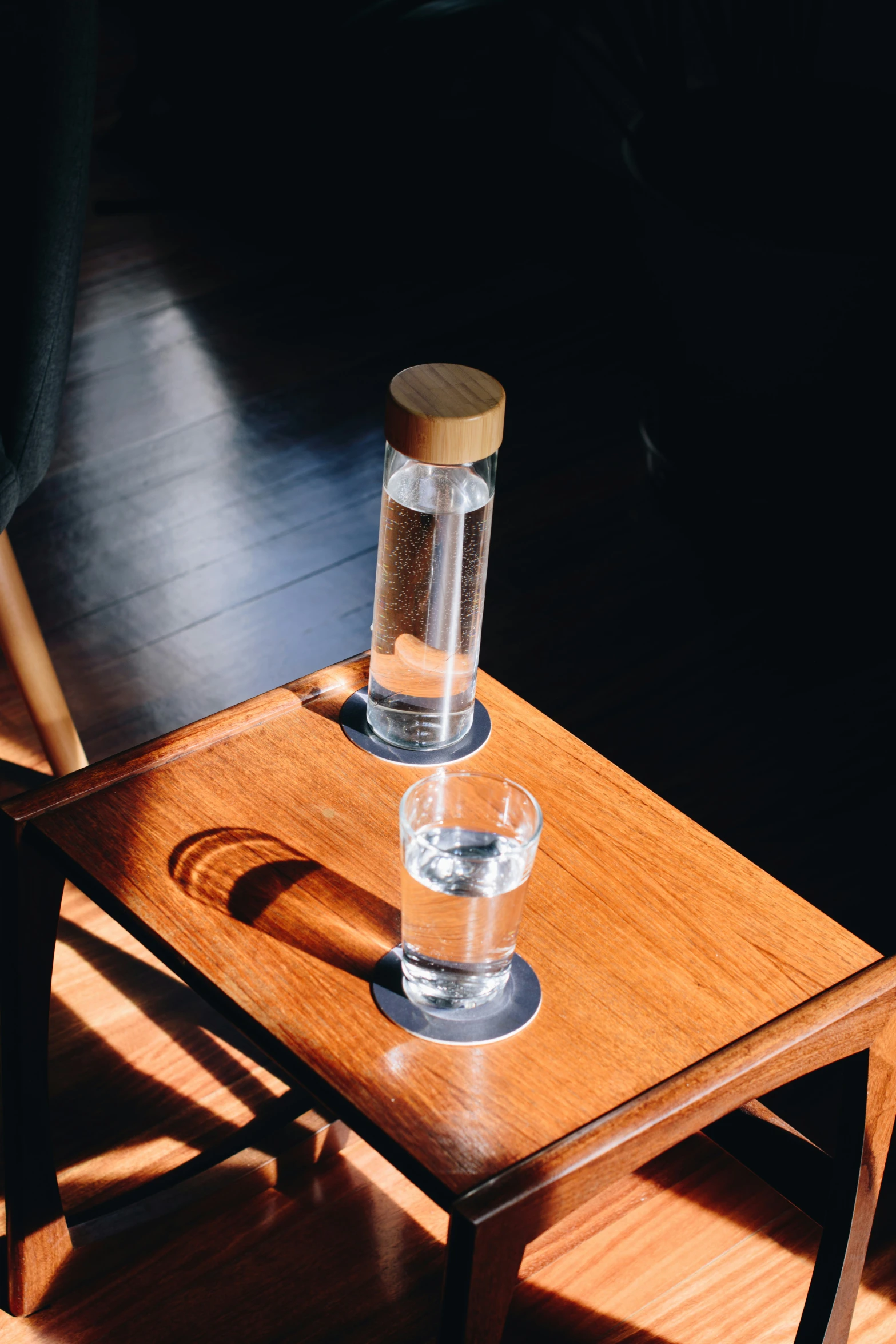 a wooden table with two glasses and a light on top