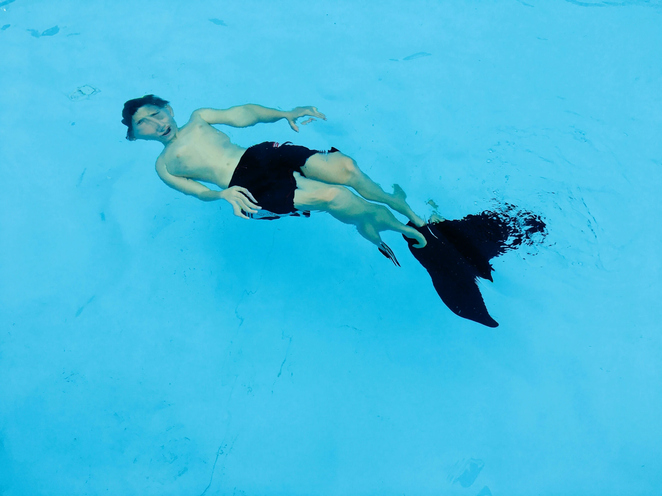 a man floating in a blue pool with his face covered