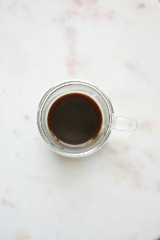 the cup is full of brown liquid sitting on the marble table