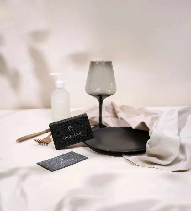 two black and white items including a hair brush, soap, and shampoo are laid on a bed