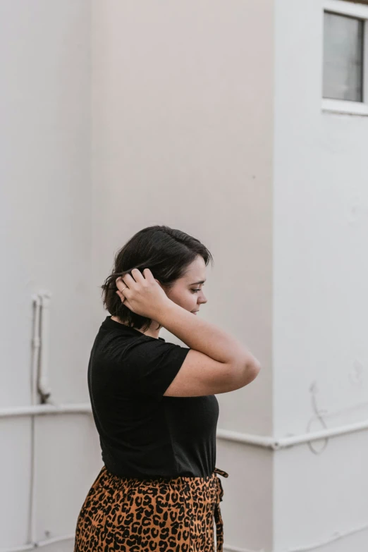 woman in black shirt standing near wall with her hands on her back