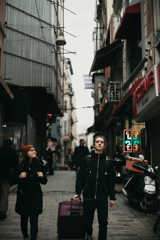 two people walk down a city street with luggage