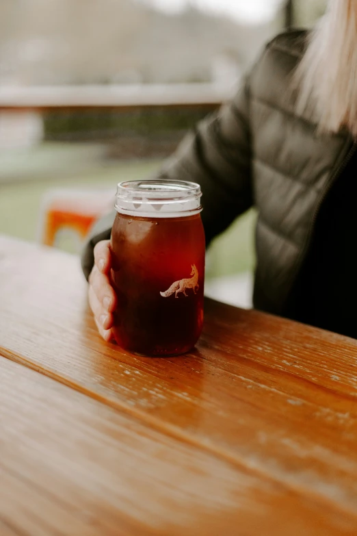 the person is holding a jar of tea sitting on the table