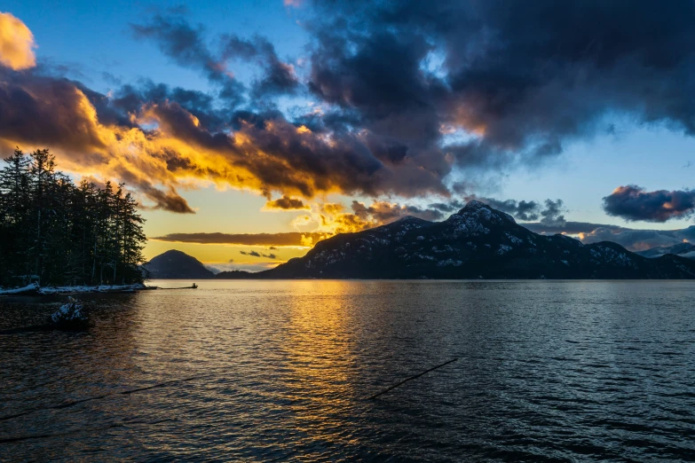 a dark water area with snow covered mountains in the background