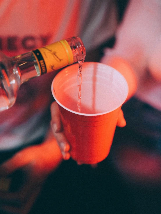 someone pouring an orange cup with white rim