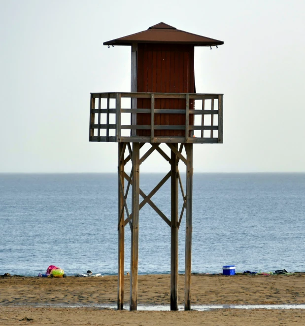 a life guard tower is at the end of an empty beach