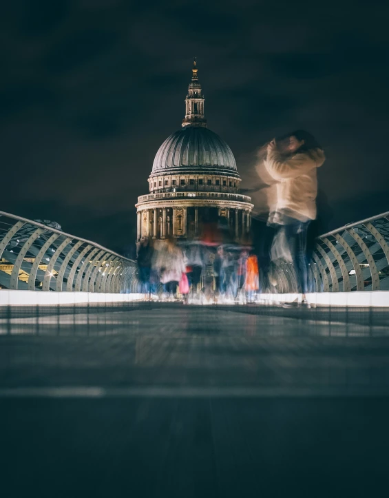 people are walking across the walkway in the evening