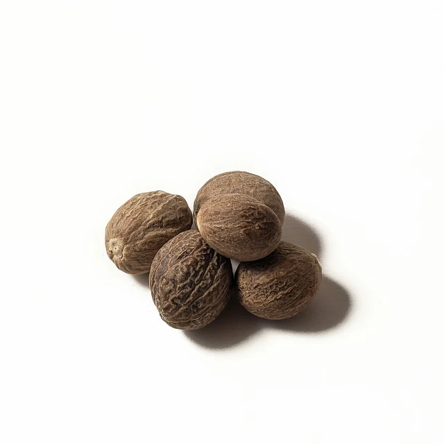 four walnuts on a white surface, one is brown