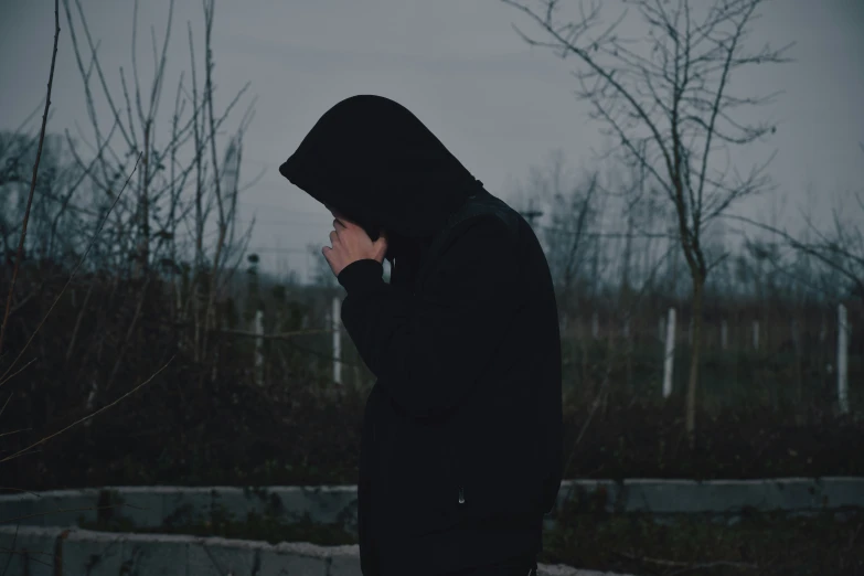 a man standing in front of trees with a hood on