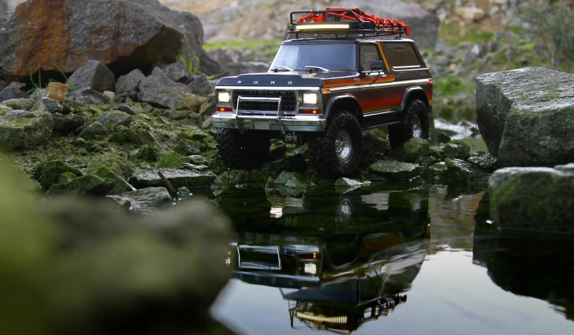 a suv driving through rocks, grass and water