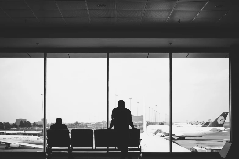 a couple looking out an airport window while their are waiting