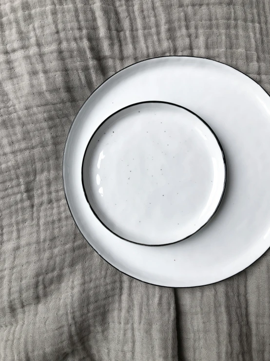 a white plate on a gray surface on top of an older plate