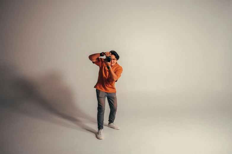 a man in an orange shirt taking a picture with his camera