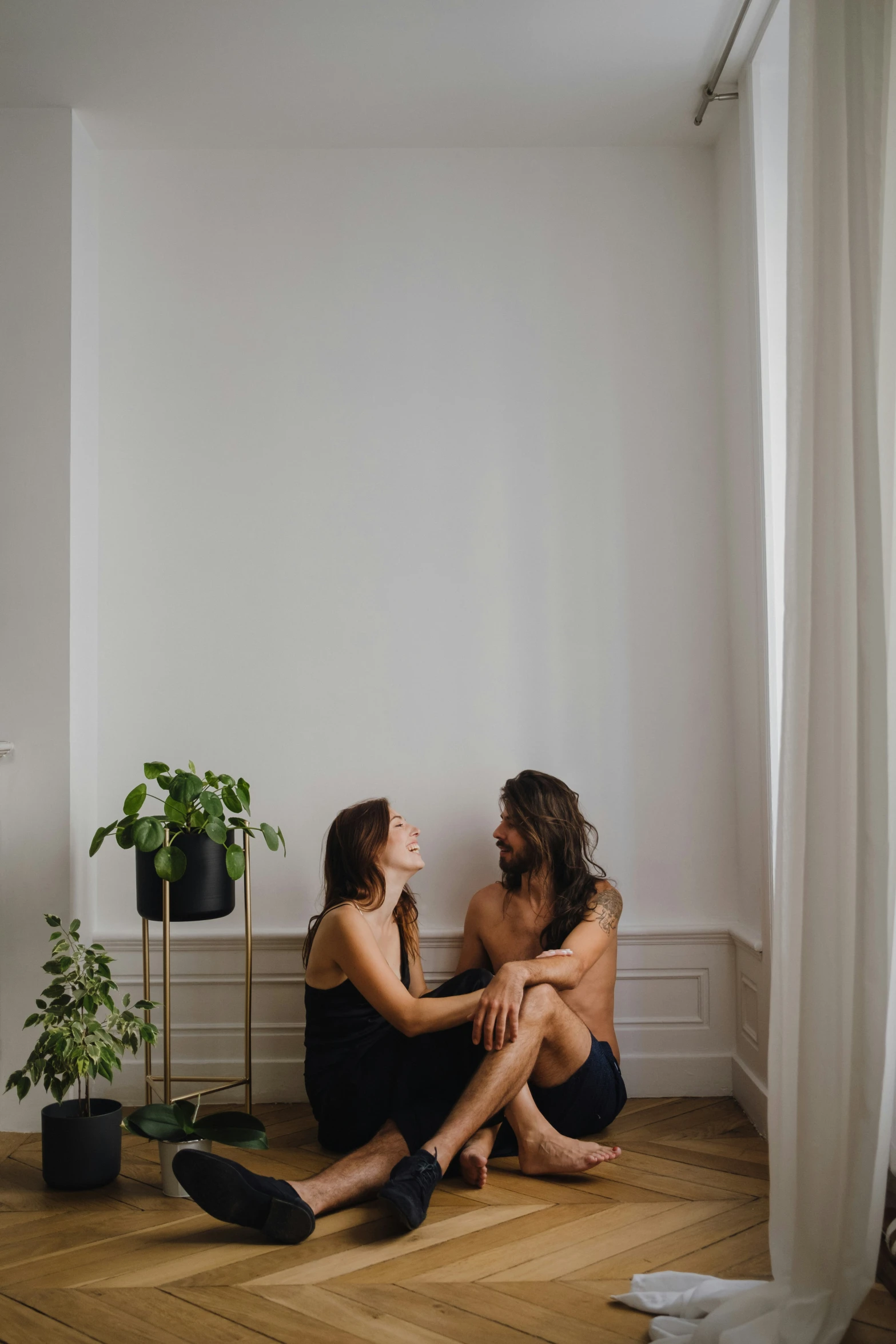 couple in black bath robes sitting on floor near window