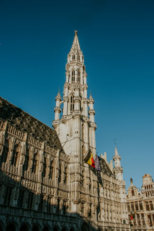 the tall tower of the building has three flags in it