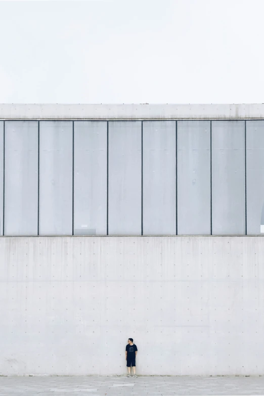 a lone person standing outside in front of some glass panels