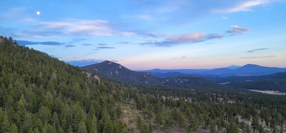 the mountains and forests are under a beautiful sky