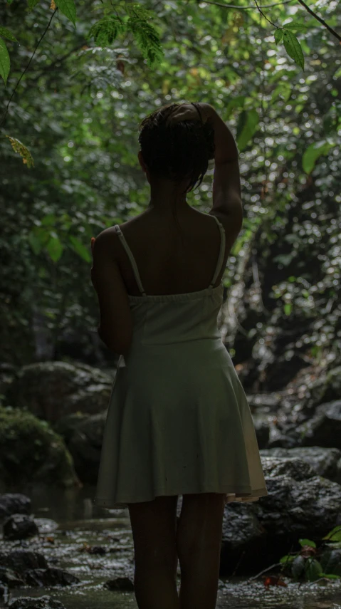 a person in a dress on the ground in the woods