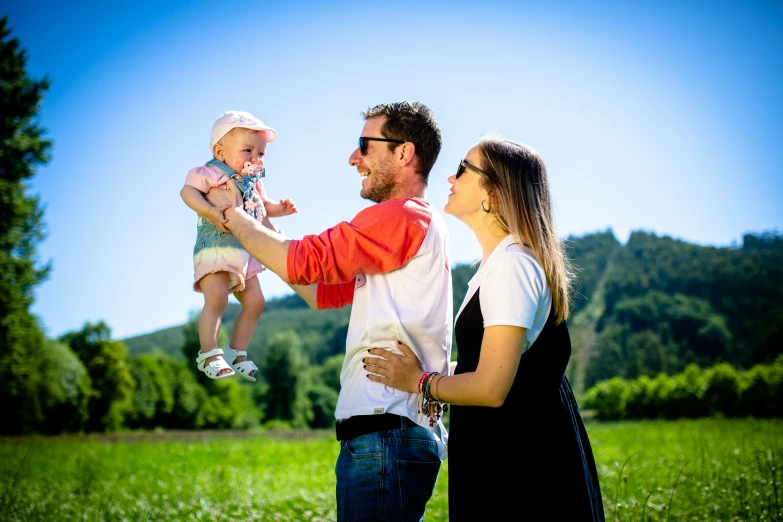 a man with sunglasses on, holding a baby and two women