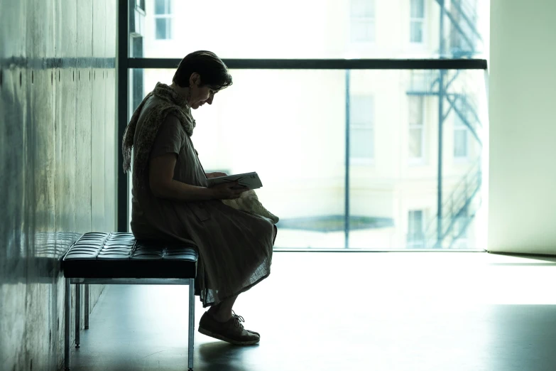 a person sits down reading on a bench in the dark