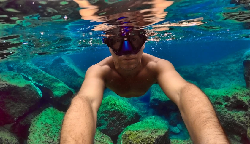 a man swimming in the water near some rocks