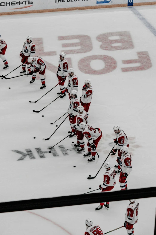 the group of players in red and white hockey uniforms are playing with a black stick