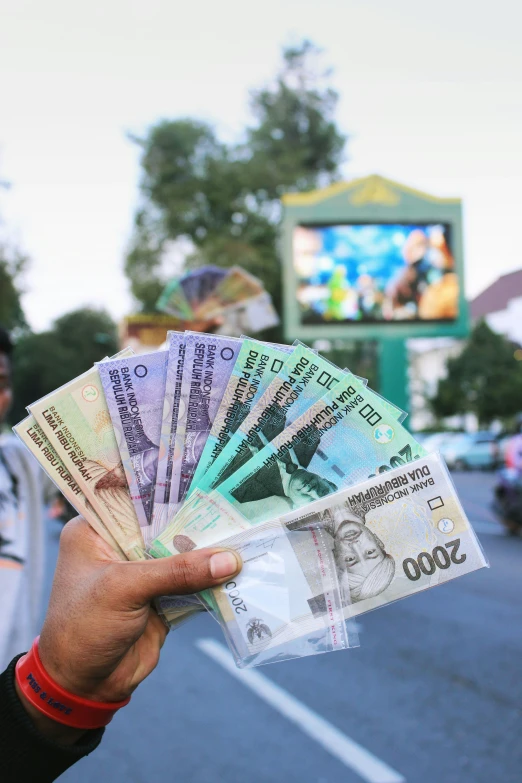 a man is holding cash in front of the tv