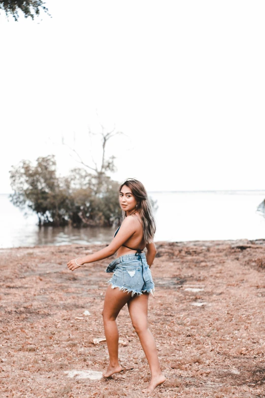 a beautiful young woman standing on top of a sandy beach