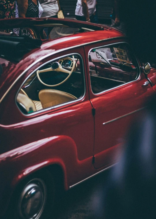 an old style red car sitting in the street