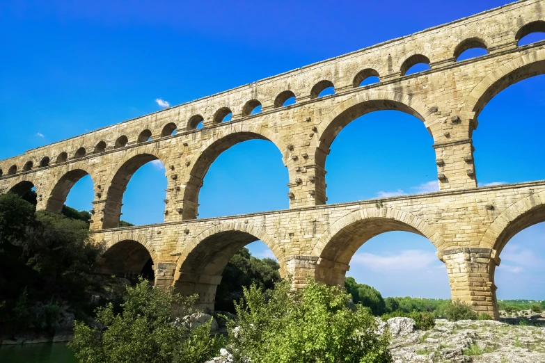 an old stone bridge with arches and greenery