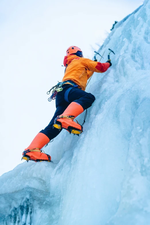 a man in an orange jacket snowboarding down a mountain