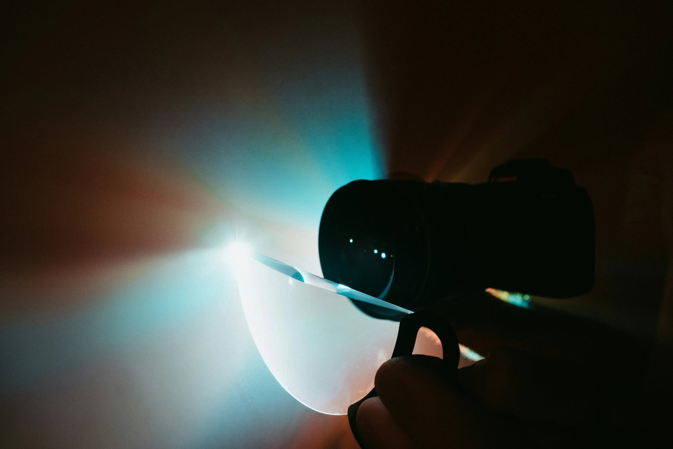 the hand holds a camera up while a light shines on the wall