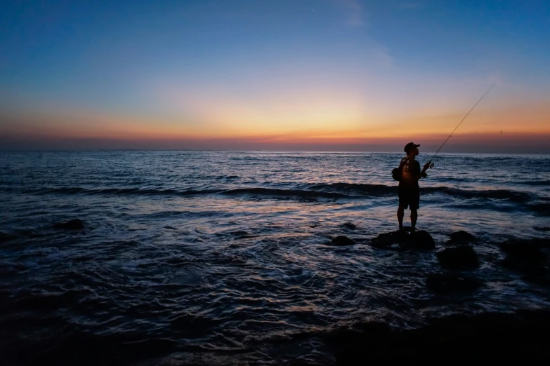 a man in black wet suit holding a fishing rod