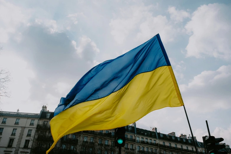 the blue and yellow flag is in front of a large building